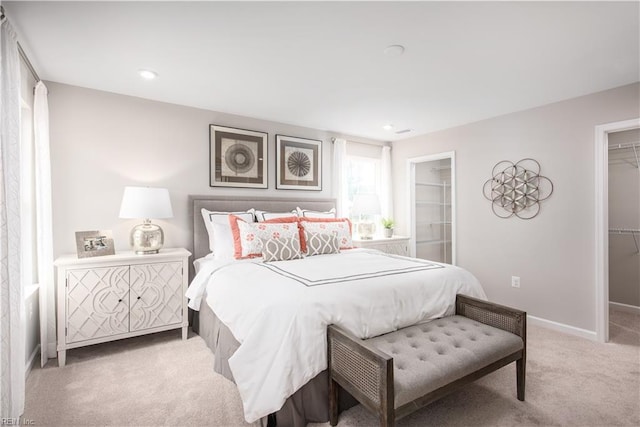 bedroom featuring light colored carpet and a spacious closet