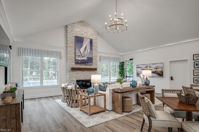 living room featuring a fireplace, high vaulted ceiling, a chandelier, and wood-type flooring