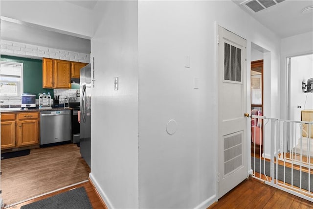 kitchen with appliances with stainless steel finishes, dark hardwood / wood-style flooring, and tasteful backsplash