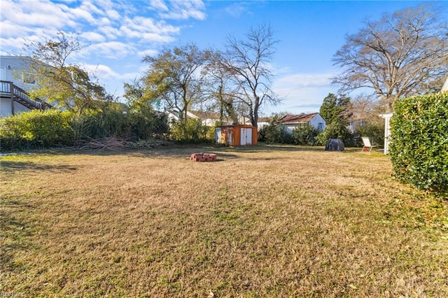 view of yard with an outdoor fire pit and a storage shed