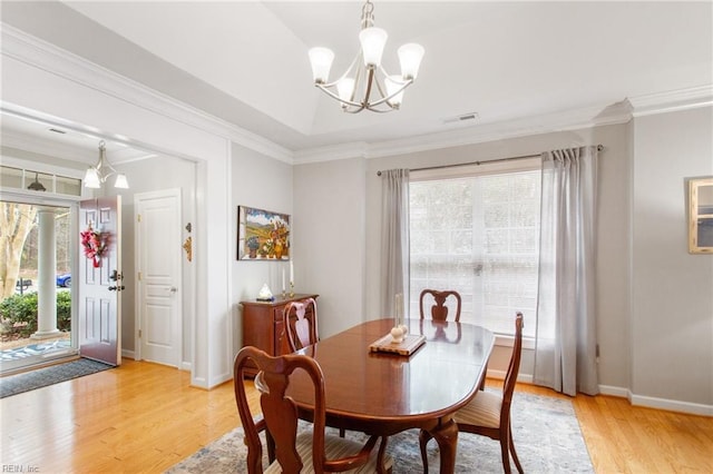 dining area featuring a notable chandelier, ornamental molding, and light wood-type flooring