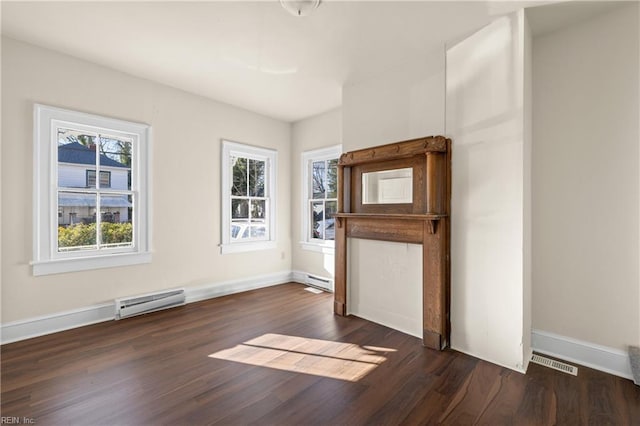 empty room featuring plenty of natural light, a baseboard heating unit, and dark hardwood / wood-style flooring