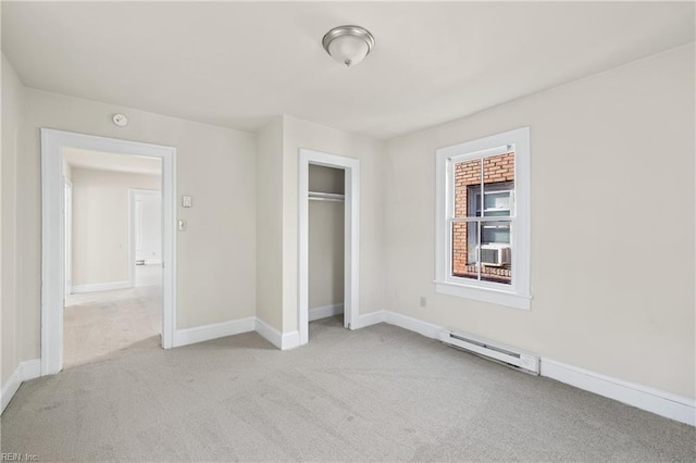 unfurnished bedroom with light colored carpet, baseboard heating, and a closet