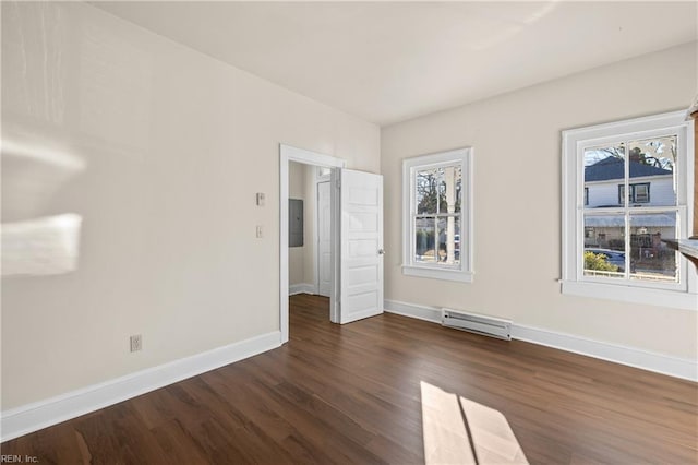 spare room with dark wood-type flooring, a baseboard radiator, and electric panel