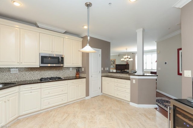 kitchen with kitchen peninsula, appliances with stainless steel finishes, decorative light fixtures, ornamental molding, and decorative backsplash