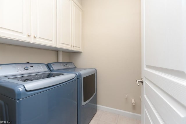 clothes washing area featuring light tile patterned flooring, cabinets, and washing machine and dryer