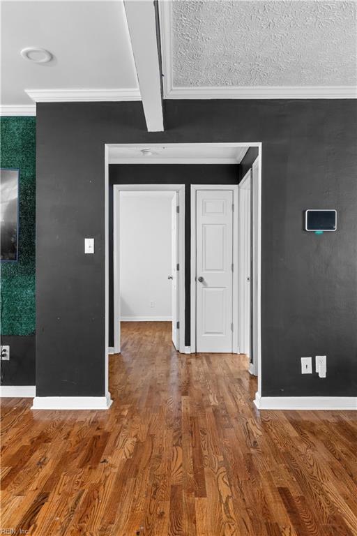 interior space with hardwood / wood-style flooring, ornamental molding, and beam ceiling