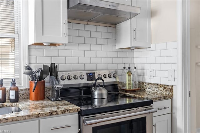 kitchen featuring white cabinetry, stainless steel range with electric stovetop, range hood, and tasteful backsplash