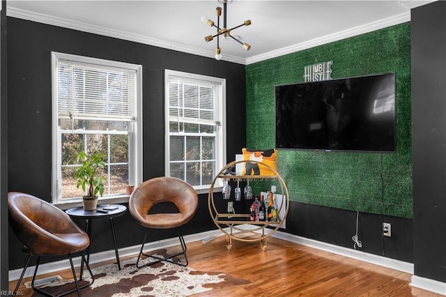 living area featuring hardwood / wood-style flooring, ornamental molding, and an inviting chandelier