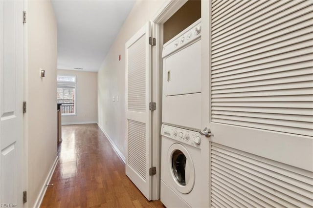 clothes washing area featuring stacked washer and clothes dryer and light hardwood / wood-style flooring