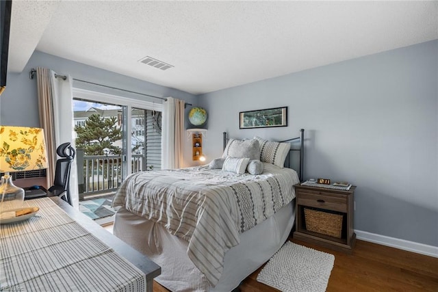 bedroom with dark hardwood / wood-style flooring, a textured ceiling, and access to outside