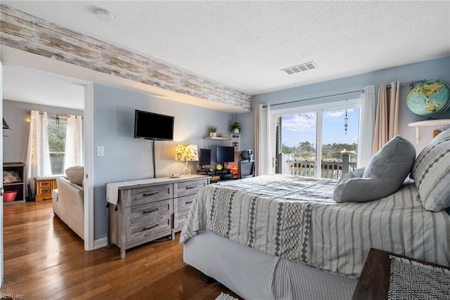 bedroom featuring a textured ceiling, dark hardwood / wood-style floors, and access to outside