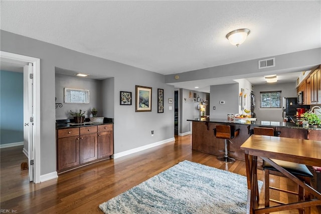 dining area with a textured ceiling and dark hardwood / wood-style flooring