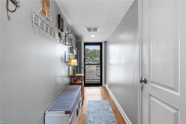 doorway to outside featuring hardwood / wood-style floors, a textured ceiling, and a wall of windows