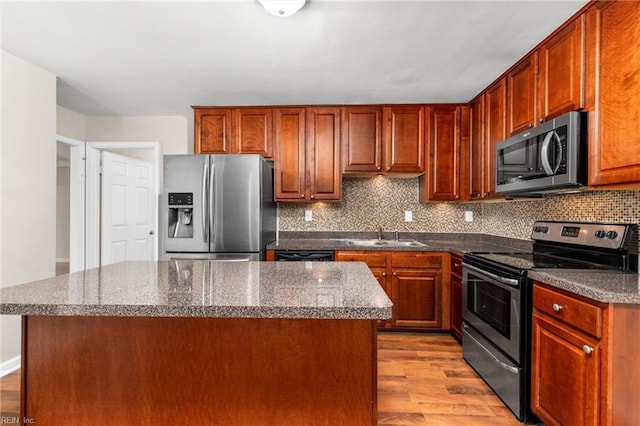 kitchen with light hardwood / wood-style flooring, sink, tasteful backsplash, a center island, and stainless steel appliances