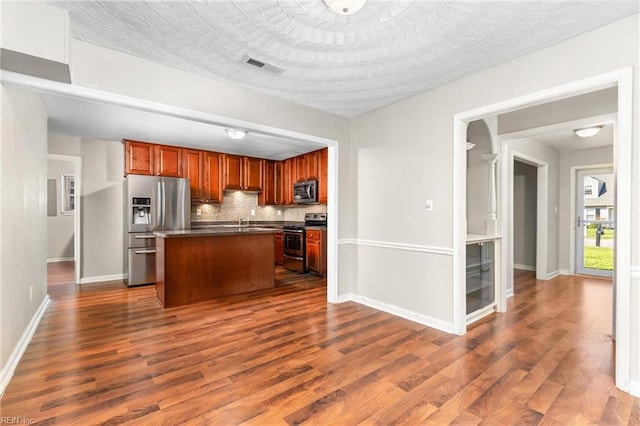 kitchen with a kitchen island, dark hardwood / wood-style floors, appliances with stainless steel finishes, and backsplash