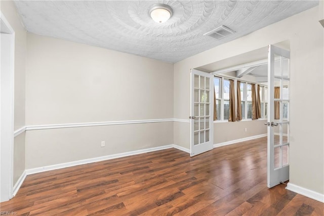 unfurnished room featuring dark hardwood / wood-style flooring, a textured ceiling, and french doors