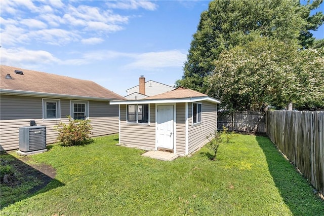 rear view of house featuring an outbuilding, a lawn, and cooling unit