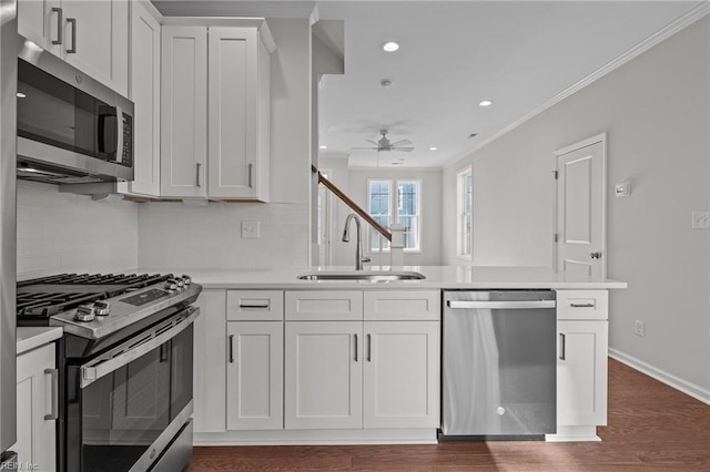 kitchen with white cabinets, stainless steel appliances, sink, kitchen peninsula, and crown molding