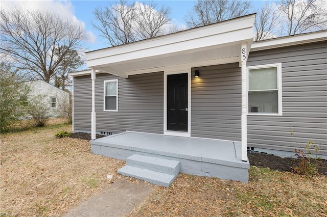 doorway to property featuring covered porch and a yard