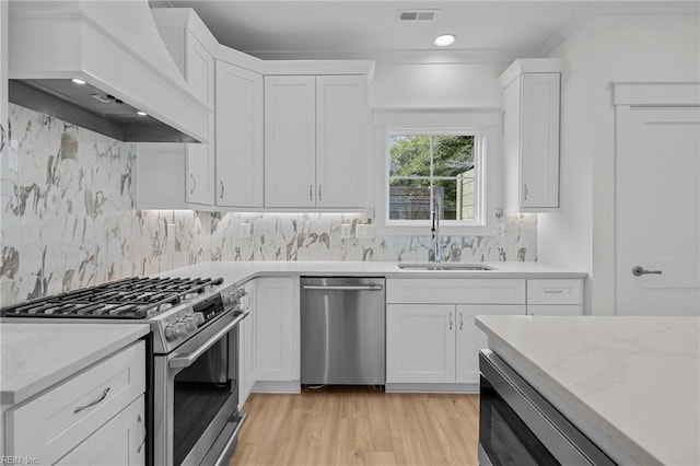 kitchen featuring sink, stainless steel appliances, custom range hood, and white cabinetry