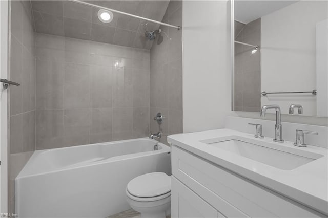 full bathroom featuring toilet, tiled shower / bath, and vanity