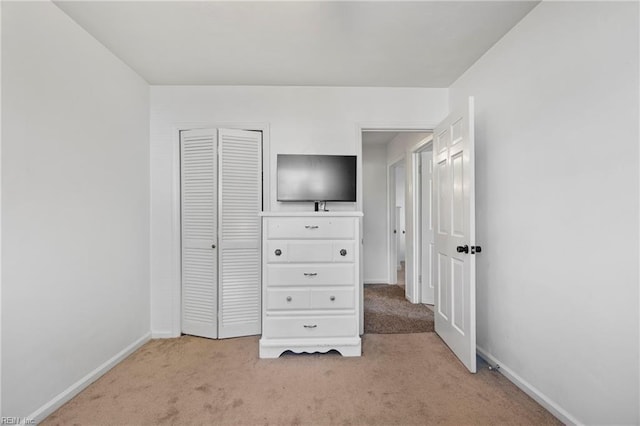 unfurnished bedroom with light colored carpet and a closet