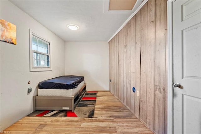 bedroom with wood walls and light hardwood / wood-style floors