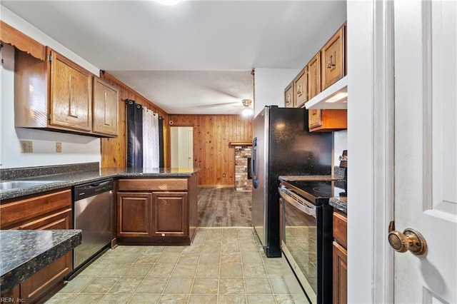 kitchen with appliances with stainless steel finishes, wooden walls, sink, kitchen peninsula, and ceiling fan