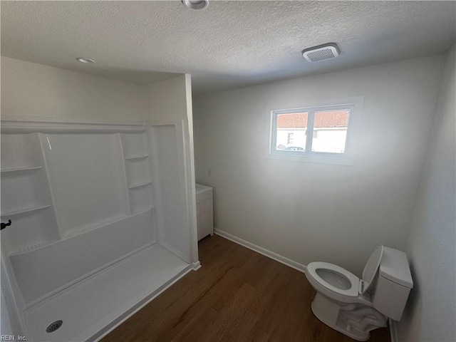 bathroom with a shower, a textured ceiling, and wood-type flooring