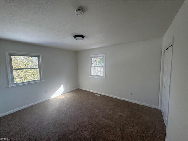 unfurnished room featuring dark carpet