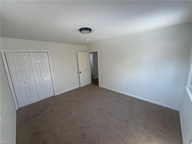 unfurnished bedroom with a closet and dark carpet