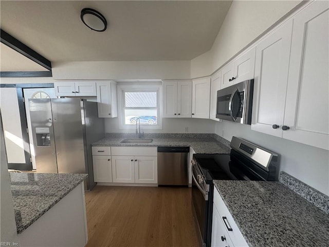 kitchen with appliances with stainless steel finishes, sink, white cabinets, dark hardwood / wood-style flooring, and stone countertops