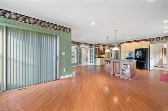 kitchen featuring a kitchen island, black refrigerator with ice dispenser, french doors, a kitchen breakfast bar, and hanging light fixtures