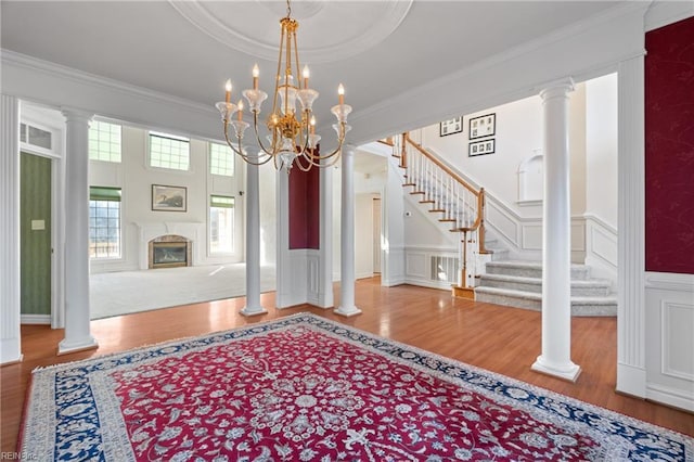 foyer with crown molding, hardwood / wood-style floors, and ornate columns