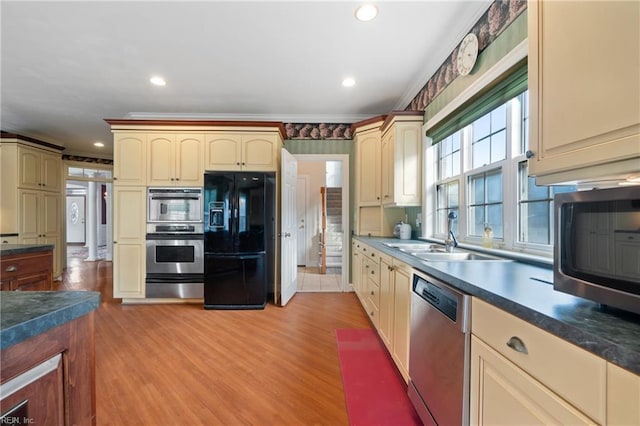 kitchen featuring sink, appliances with stainless steel finishes, light hardwood / wood-style flooring, and ornamental molding