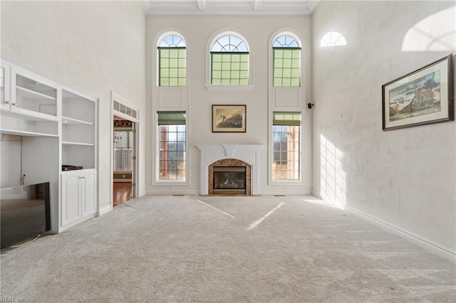 unfurnished living room with built in shelves, a high end fireplace, plenty of natural light, and carpet floors