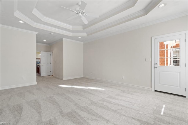 empty room featuring ceiling fan, a raised ceiling, ornamental molding, and light carpet