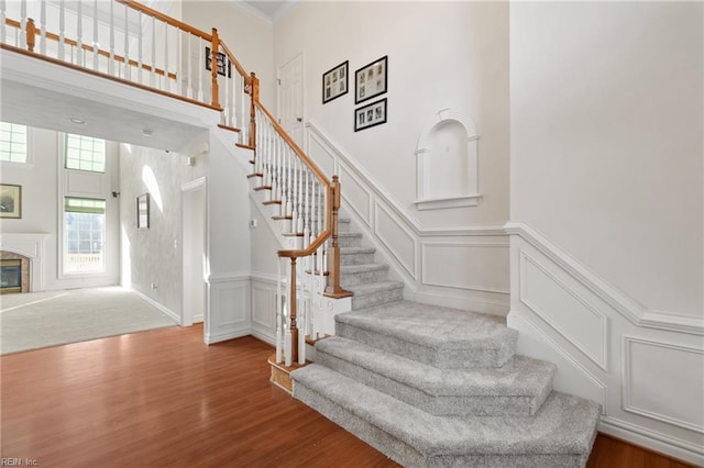 stairs with hardwood / wood-style floors and a towering ceiling