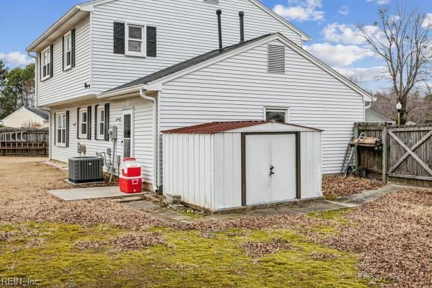 rear view of property featuring central AC unit, a lawn, and a shed