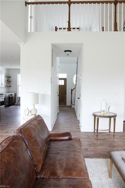 corridor with hardwood / wood-style flooring, a healthy amount of sunlight, and a towering ceiling