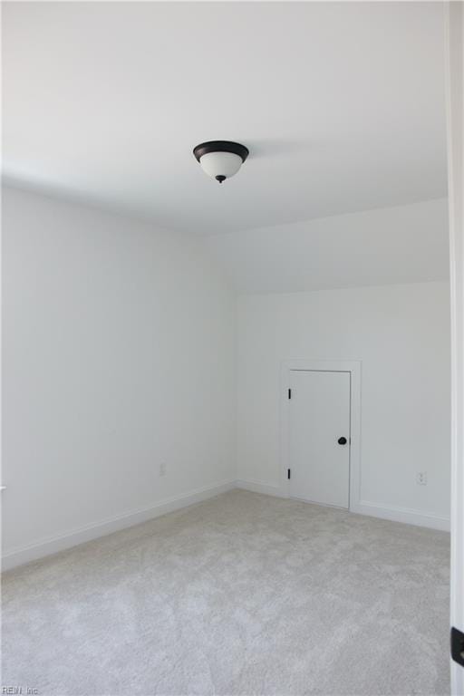 carpeted empty room featuring lofted ceiling