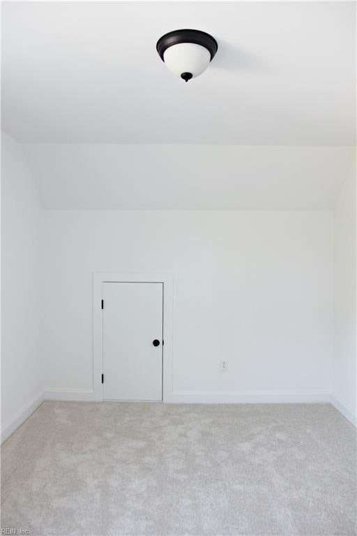 bonus room with lofted ceiling and light colored carpet