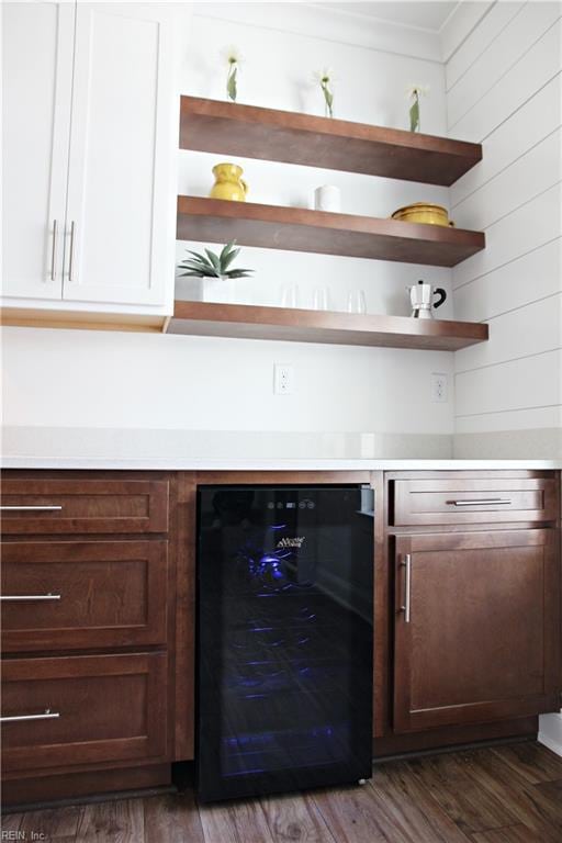 bar with wine cooler, dark brown cabinetry, wooden walls, dark hardwood / wood-style flooring, and white cabinets