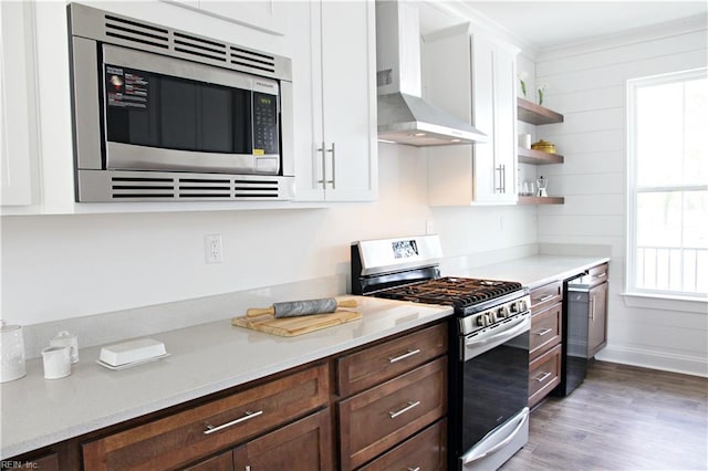 kitchen with dark hardwood / wood-style floors, white cabinetry, dark brown cabinetry, stainless steel appliances, and wall chimney range hood