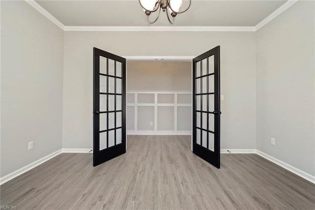 unfurnished room with french doors, an inviting chandelier, crown molding, and hardwood / wood-style floors