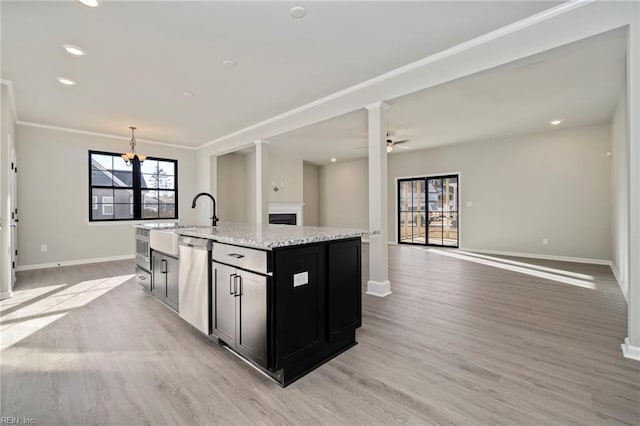 kitchen with sink, light hardwood / wood-style flooring, dishwasher, an island with sink, and light stone countertops