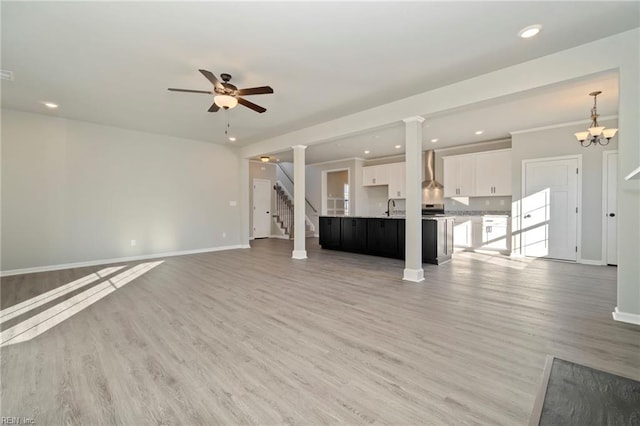 unfurnished living room with sink, light hardwood / wood-style flooring, ceiling fan, and ornate columns