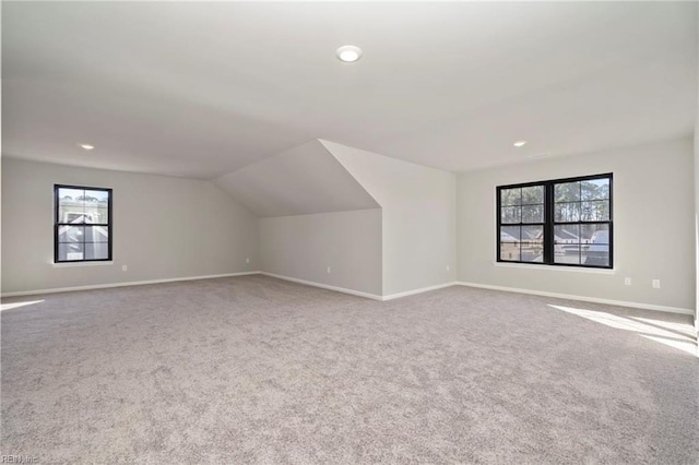 additional living space featuring vaulted ceiling, plenty of natural light, and carpet flooring