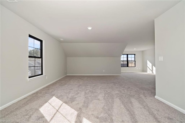 additional living space with vaulted ceiling and light carpet